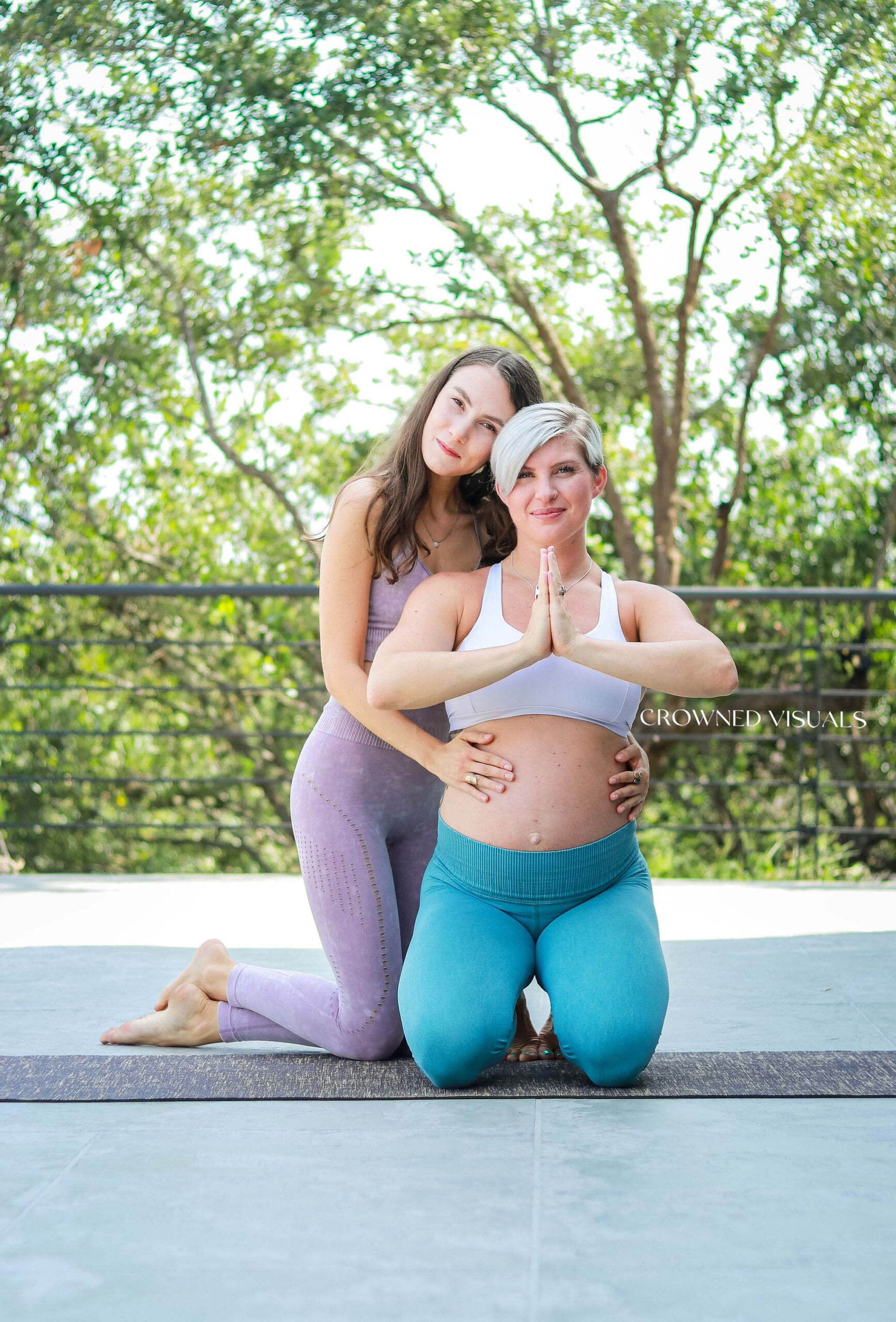 Pregnant mother doing prenatal yoga supported by prenatal yoga instructor